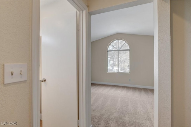 corridor featuring vaulted ceiling and carpet