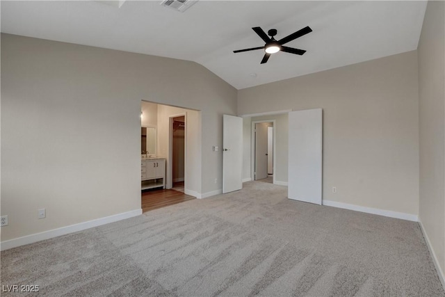 unfurnished bedroom with carpet flooring, vaulted ceiling, a walk in closet, and connected bathroom