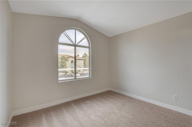 carpeted empty room featuring lofted ceiling