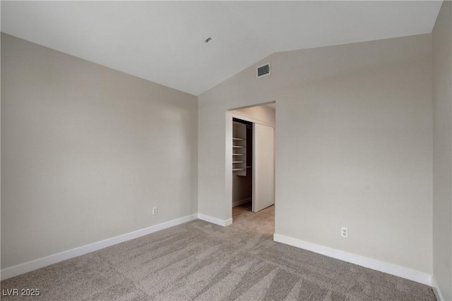 carpeted empty room featuring vaulted ceiling