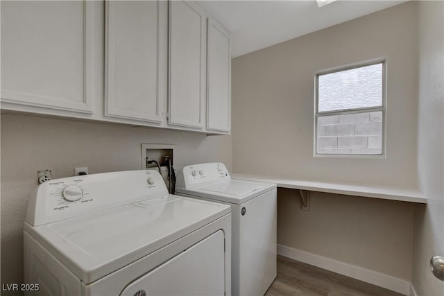 laundry area featuring cabinets, washer and clothes dryer, and light hardwood / wood-style flooring