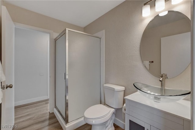 bathroom with toilet, a shower with door, hardwood / wood-style floors, and vanity