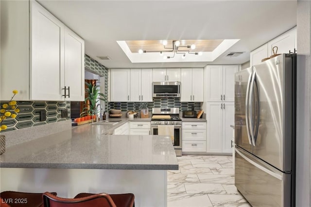 kitchen featuring stainless steel appliances, sink, white cabinets, and kitchen peninsula