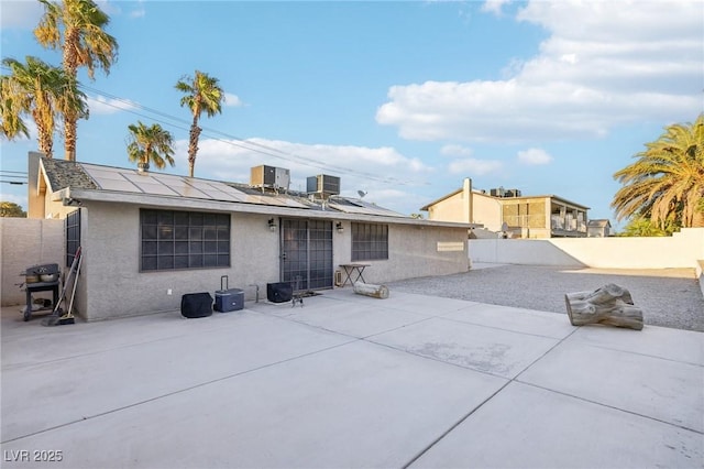 back of property with solar panels, central AC unit, and a patio area