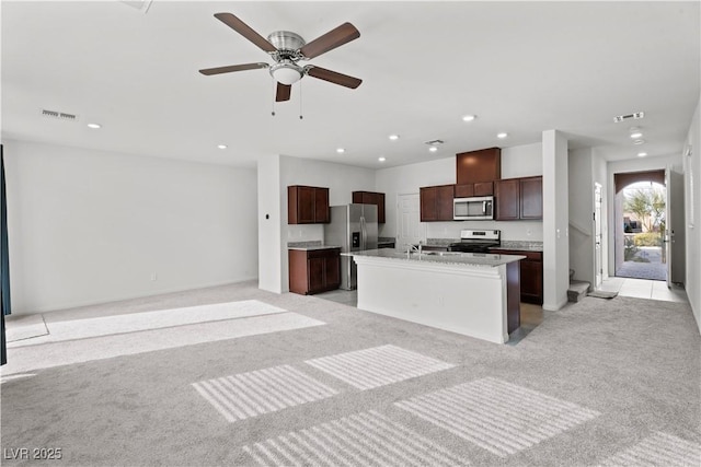 kitchen with appliances with stainless steel finishes, sink, ceiling fan, light carpet, and a center island with sink