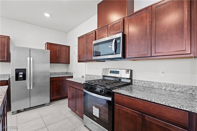 kitchen with light stone counters, light tile patterned floors, and stainless steel appliances