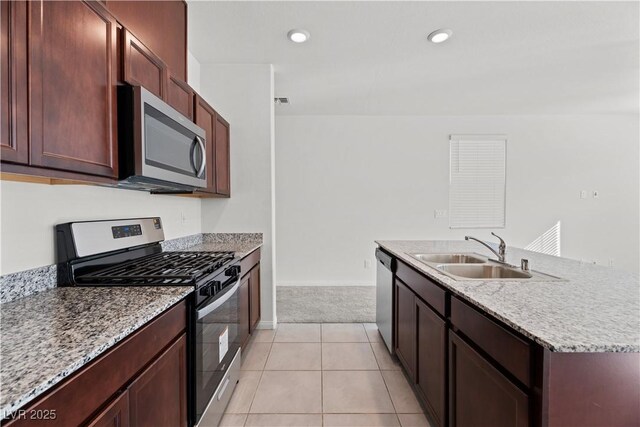 kitchen featuring sink, a kitchen island with sink, stainless steel appliances, light stone counters, and light colored carpet