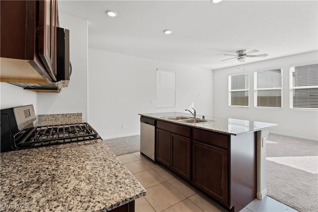 kitchen featuring sink, stainless steel appliances, light stone counters, a center island with sink, and light carpet