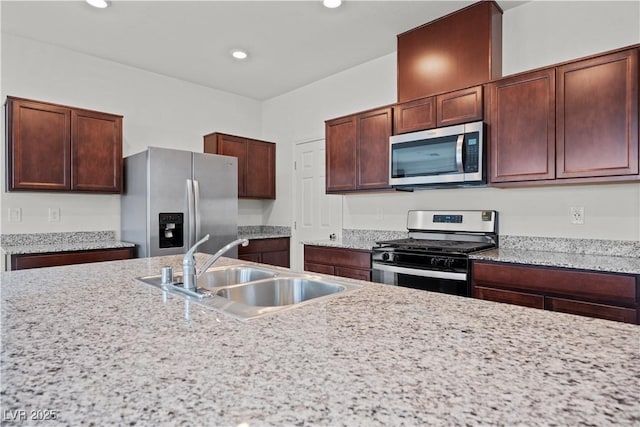 kitchen featuring light stone counters, sink, and appliances with stainless steel finishes