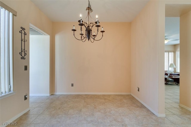 tiled spare room with ceiling fan with notable chandelier