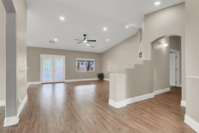 unfurnished living room featuring high vaulted ceiling, french doors, ceiling fan, and light wood-type flooring