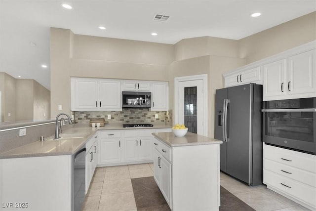 kitchen featuring sink, white cabinetry, stainless steel appliances, tasteful backsplash, and a kitchen island