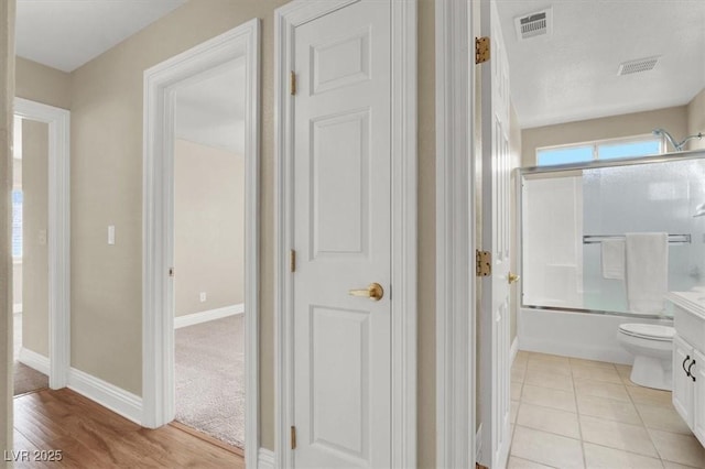 full bathroom with vanity, tile patterned floors, shower / bath combination with glass door, and toilet