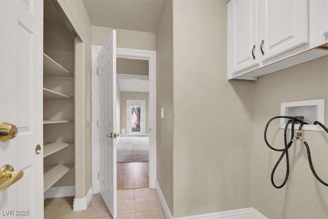 laundry area with washer hookup, light tile patterned floors, and cabinets