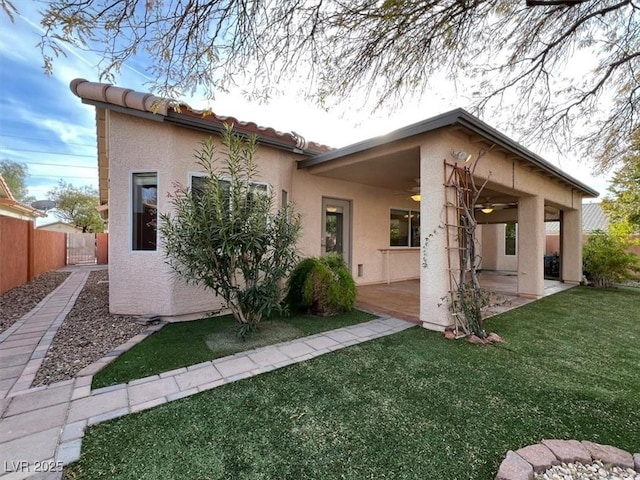 back of property featuring ceiling fan, a patio area, and a lawn