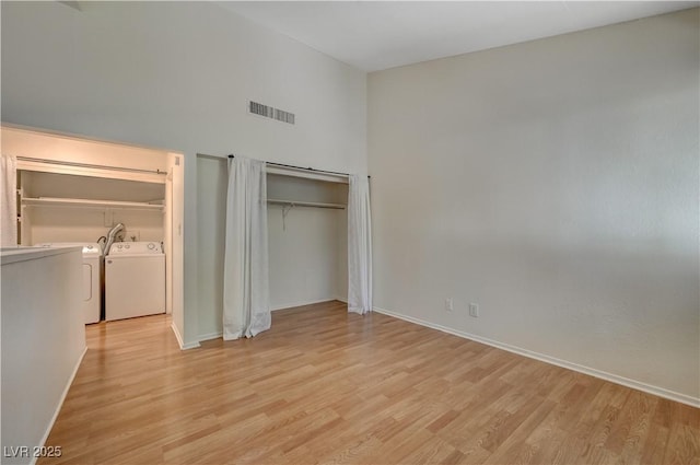 unfurnished bedroom featuring washer and dryer, light wood-type flooring, and a closet