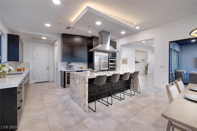 kitchen featuring stainless steel built in refrigerator, sink, a large island, decorative backsplash, and exhaust hood