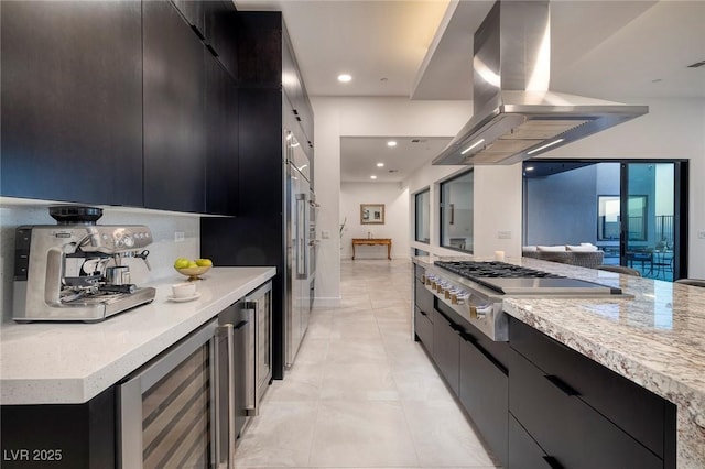 kitchen featuring stainless steel gas cooktop, light tile patterned floors, island exhaust hood, beverage cooler, and light stone countertops