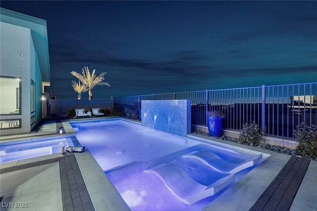 pool at night featuring a patio