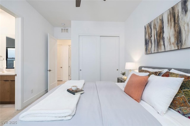 bedroom with ceiling fan, ensuite bath, sink, and a closet