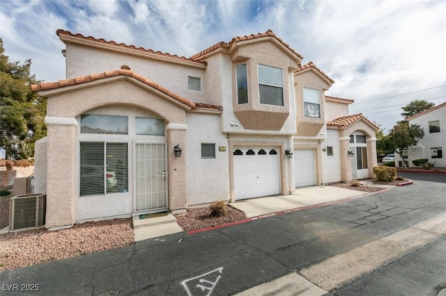 mediterranean / spanish home with a garage and central AC unit