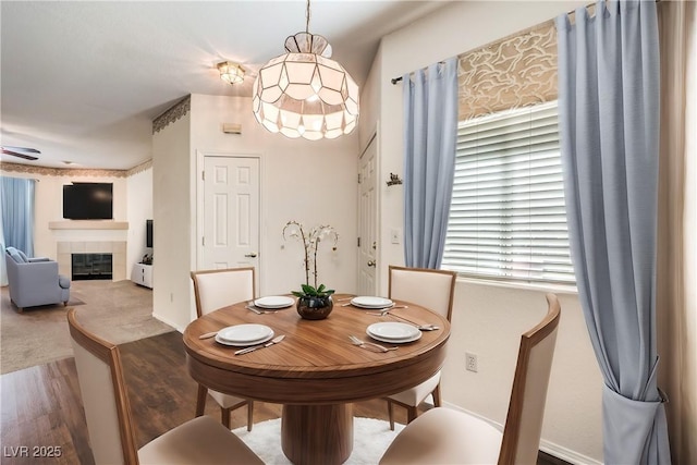 dining area with wood-type flooring and a tile fireplace