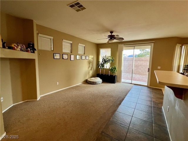 interior space with ceiling fan and dark colored carpet