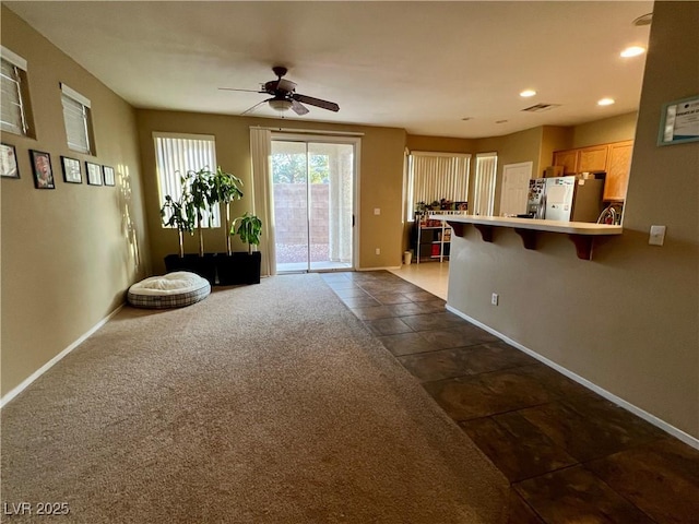 kitchen with stainless steel refrigerator, a kitchen breakfast bar, ceiling fan, kitchen peninsula, and dark carpet