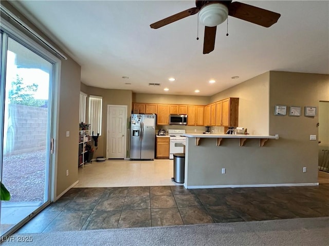 kitchen featuring ceiling fan, stainless steel appliances, a kitchen breakfast bar, and kitchen peninsula