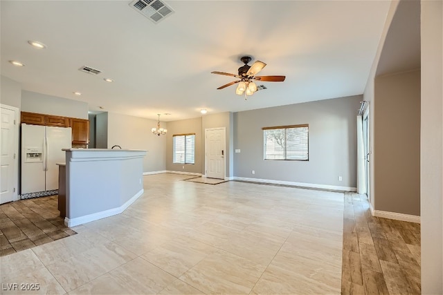 unfurnished living room with ceiling fan with notable chandelier