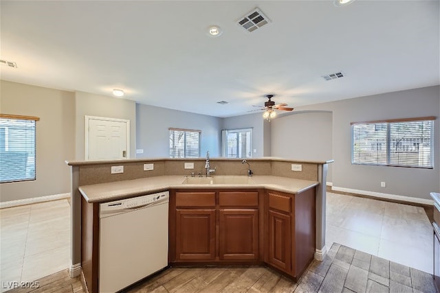 kitchen featuring sink, plenty of natural light, white dishwasher, and an island with sink