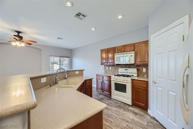 kitchen featuring sink, white appliances, decorative backsplash, and ceiling fan