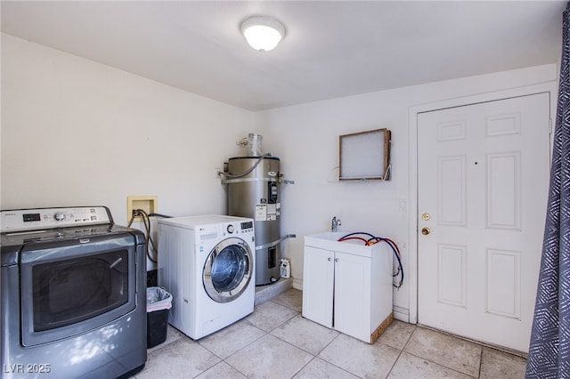 clothes washing area featuring cabinets, independent washer and dryer, water heater, and light tile patterned floors