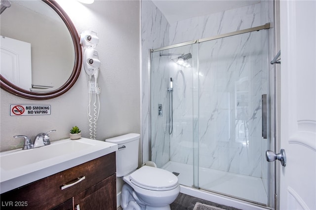 bathroom with vanity, a shower with shower door, and toilet