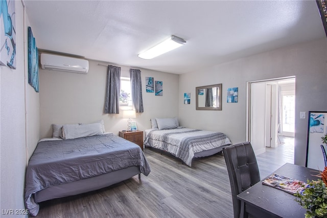 bedroom with hardwood / wood-style flooring and a wall mounted air conditioner