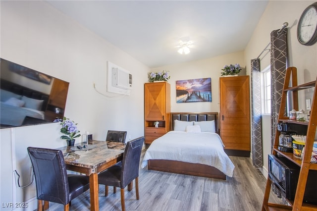 bedroom featuring a wall mounted air conditioner and hardwood / wood-style floors