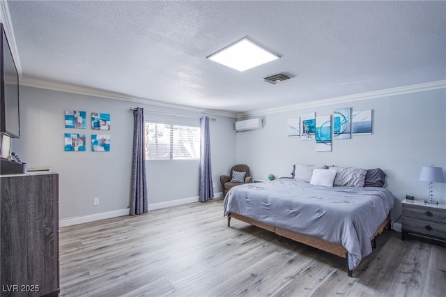 bedroom with ornamental molding, a wall mounted AC, and light hardwood / wood-style flooring