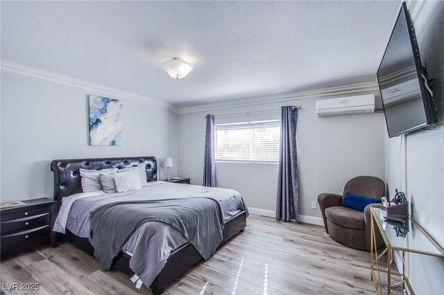 bedroom featuring ornamental molding, light wood-type flooring, and an AC wall unit