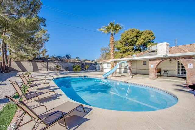 view of swimming pool featuring a water slide and a patio area