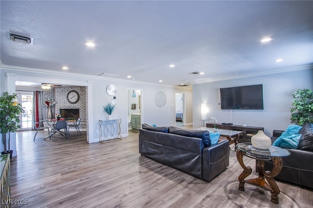 living room featuring ornamental molding, a brick fireplace, ceiling fan, and light hardwood / wood-style floors