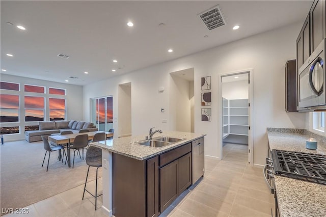 kitchen featuring an island with sink, appliances with stainless steel finishes, sink, and light tile patterned flooring