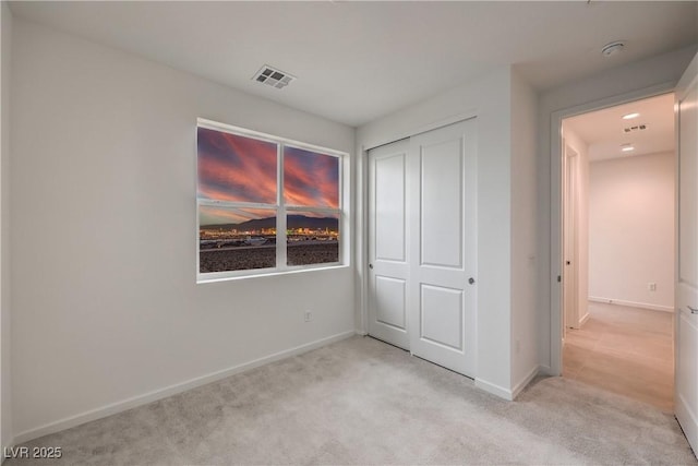 unfurnished bedroom featuring light carpet and a closet