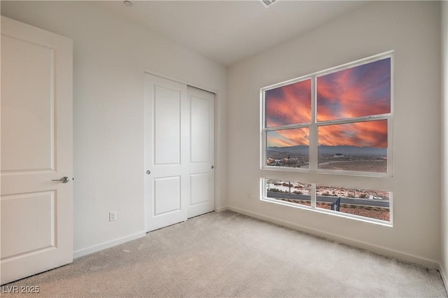 unfurnished bedroom featuring light colored carpet and a closet