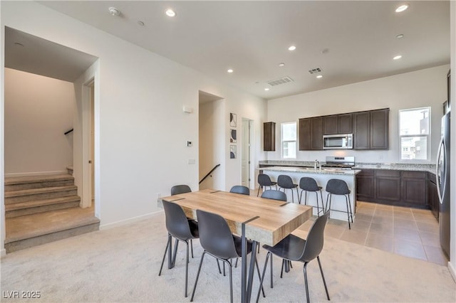 dining area featuring light carpet, sink, and plenty of natural light