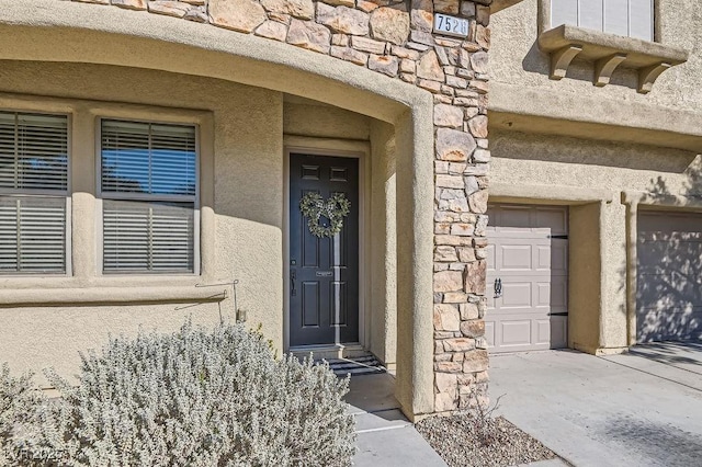 doorway to property with stone siding, concrete driveway, and stucco siding