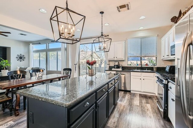 kitchen featuring appliances with stainless steel finishes, decorative light fixtures, a center island, and white cabinets