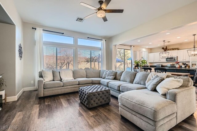 living room with dark hardwood / wood-style floors and ceiling fan with notable chandelier