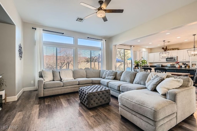 living area featuring dark wood-style floors, recessed lighting, visible vents, baseboards, and ceiling fan with notable chandelier