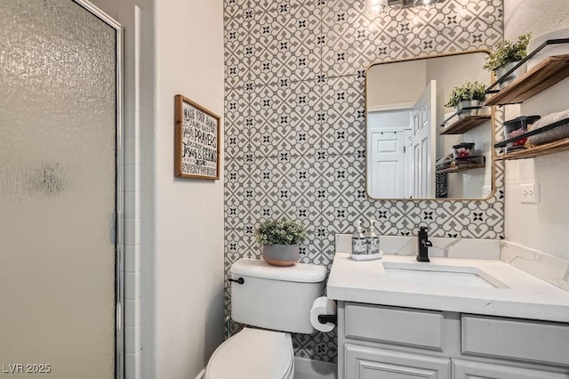 bathroom featuring a shower with door, vanity, and toilet