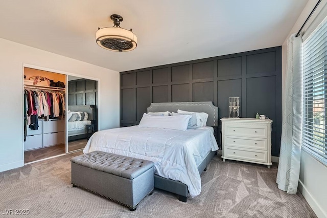 bedroom featuring light carpet, baseboards, a decorative wall, and a closet